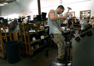 
Using his weight for stability, James Dobberstein attaches the sole of a new boot in the White's Outdoor factory.
 (The Spokesman-Review)