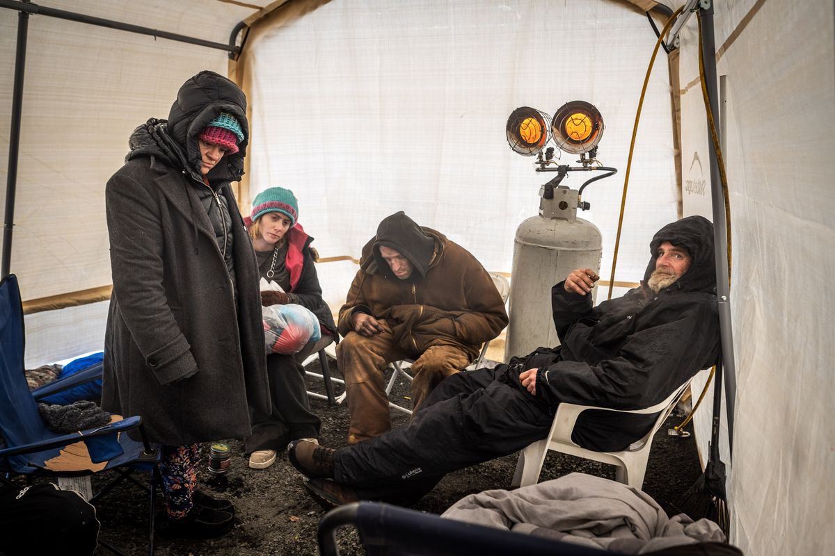 Homeless residents of Camp Hope huddle around a space heater in a warming tent on Wednesday.  (COLIN MULVANY/THE SPOKESMAN-REVIEW)