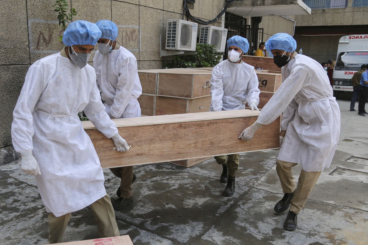 Jammu and Kashmir State Disaster Response Force soldiers carry empty coffins for transporting bodies of people who died of COVID-19 outside government medical hospital in Jammu, India, Wednesday, May 19, 2021.  (Channi Anand)