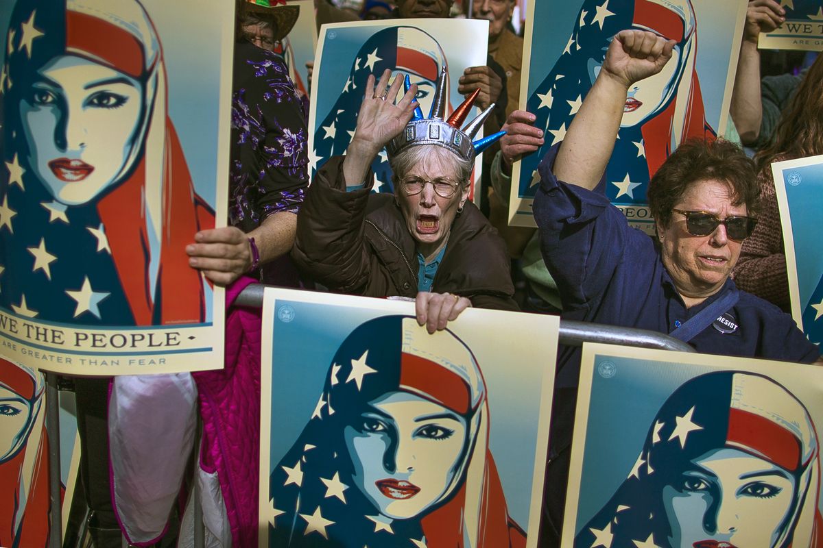 In this Sunday, Feb. 19, 2017 photo, people carry posters during a rally against President Donald Trump