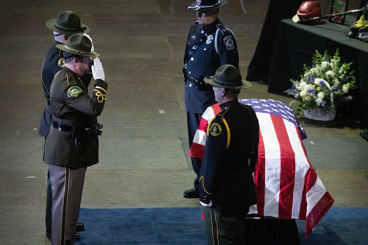 Law enforcement officers salute the casket of Everett Police Officer Dan Rocha at a memorial service at Angel of the Winds Arena on Monday in downtown Everett.  (Ken Lambert)