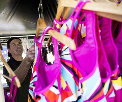 Jake Jansen stocks women's triathlon performance clothes on a rack inside the Zoot booth, Wednesday, at City Park. (Loren Benoit/Coeur d'Alene Press)