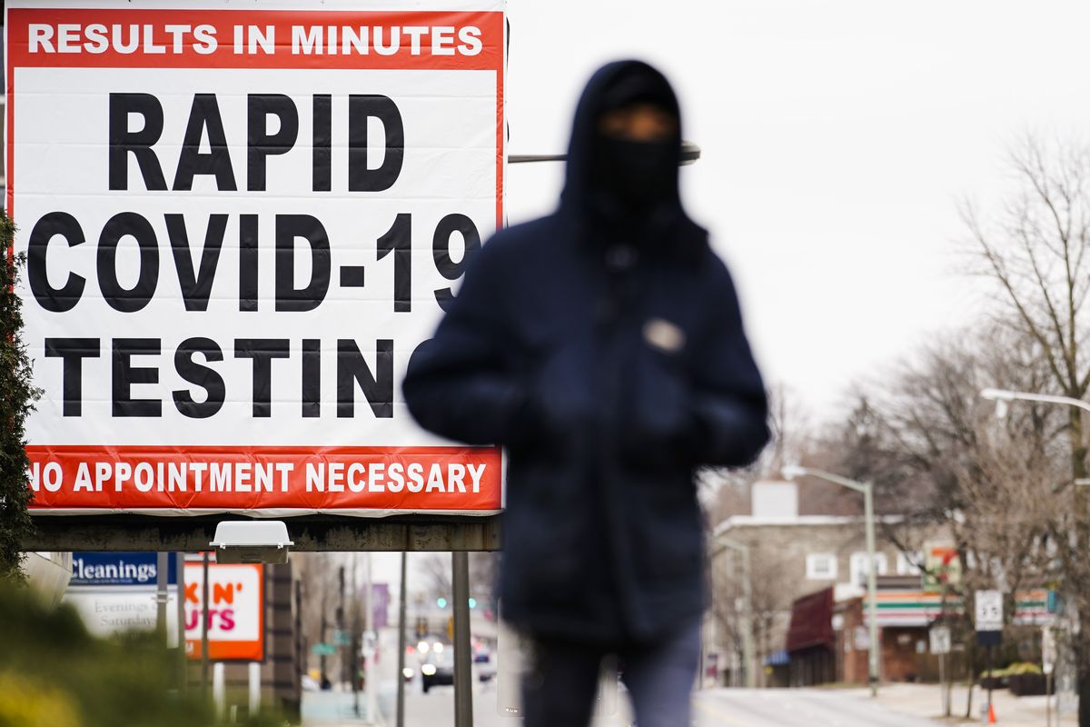 FILE - In this Jan. 25, 2021, file photo, a person wearing face mask as a precaution against the coronavirus walks near a sign advertising a rapid COVID-19 testing site in Philadelphia. U.S. healthy officials say that most fully vaccinated Americans can skip testing for COVID-19, even if they were exposed to someone infected.  (Matt Rourke)