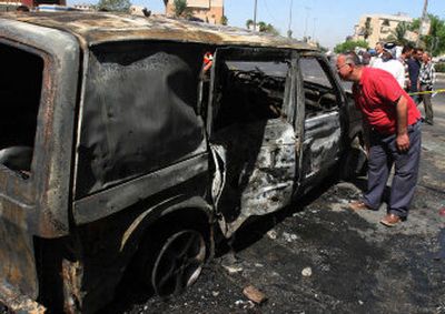 
An man inspects a vehicle after a car bomb exploded Tuesday in Baghdad. The blast killed four people, including  a police officer. 
 (Associated Press / The Spokesman-Review)