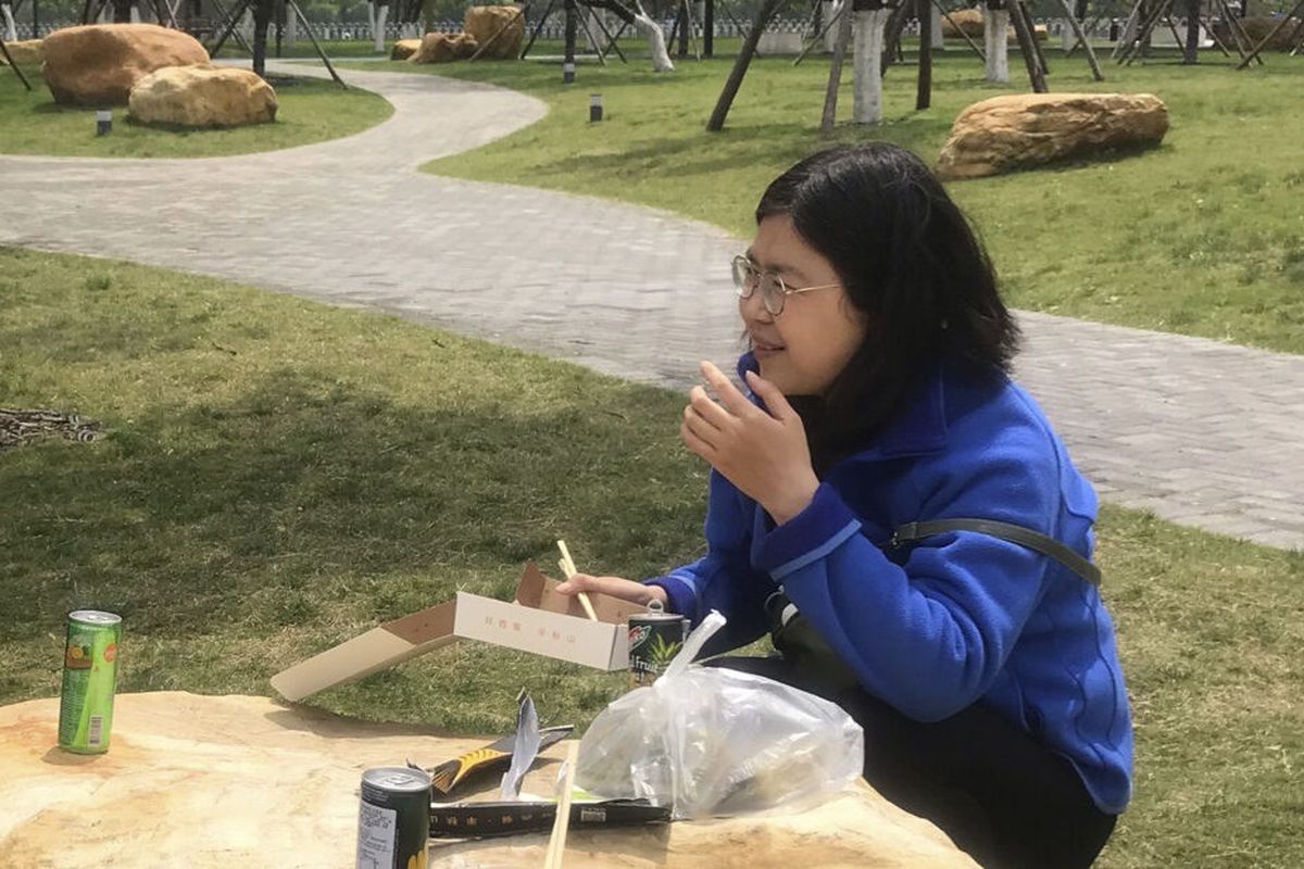 In this photo taken April 14, 2020 and released by Melanie Wang, Zhang Zhan eats a meal at a park during a visit to Wuhan in central China