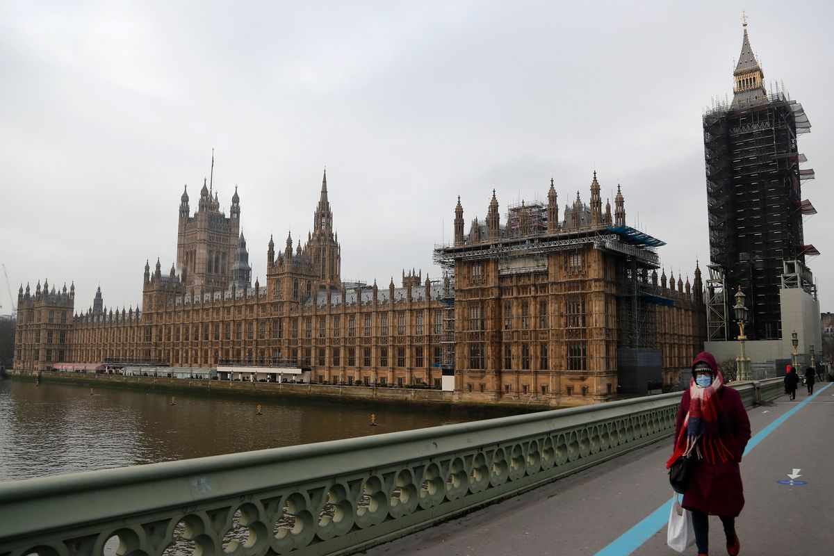 FILE - A woman wearing a face mask, walks across Westminster Bridge past the Houses of Parliament in London, Jan. 8, 2021. British parliamentary authorities say they are calling in the police after a newspaper reported that traces of cocaine had been found at numerous sites in Parliament. The Sunday Times on Sunday, Dec. 5 reported that traces of cocaine were found in 11 locations that are only accessible by accredited parliamentary lawmakers, staff and journalists, including a washroom near Prime Minister Boris Johnson’s parliamentary office.  (Frank Augstein)