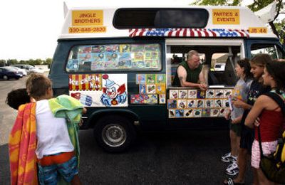 
Lewis McClung serves a group of children ice cream and other frozen treats from the Jingle Brothers' Co. truck outside the Dogwood Park Pool in North Canton, Ohio, Tuesday. Business is booming for the old-fashioned ice cream truck business, now serving nostalgia alongside modern-day munchies.  
 (Associated Press / The Spokesman-Review)