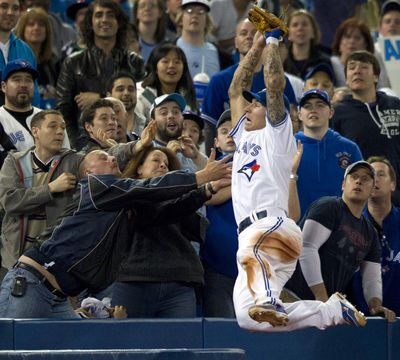 Blue Jays third baseman Brett Lawrie leaps into the crowd to catch a foul pop fly in the ninth inning of Sunday’s game in Toronto. (Associated Press)