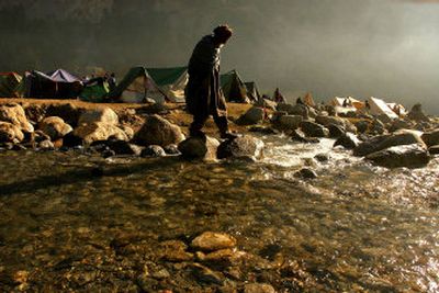 
A man crosses a river in a camp for displaced people on the outskirts of Balakot, Pakistan, on Saturday. A massive earthquake across a section of the Himalayan range that killed an estimated 79,000 people and left more than 3 million homeless has also created one of the most logistically challenging disasters.
 (Associated Press / The Spokesman-Review)