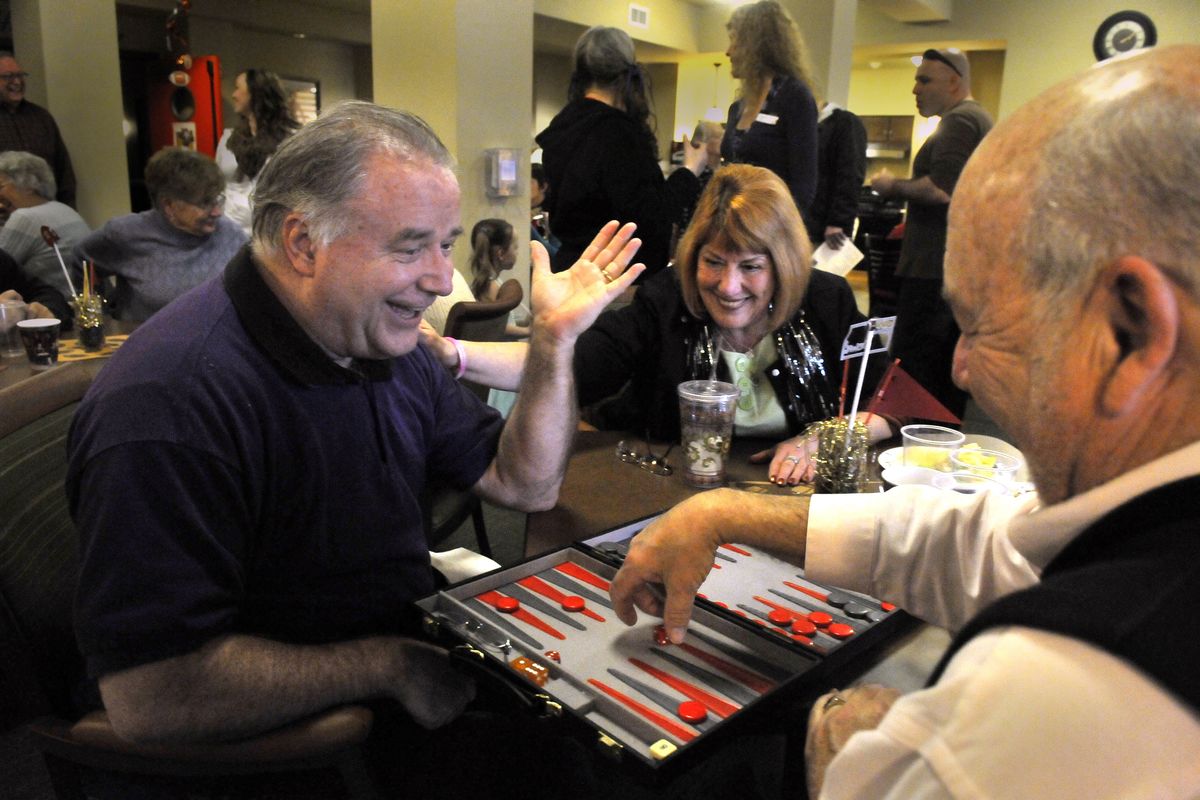 John Egley, left, laughs during a game of backgammon with Duane Goetz, right, Sunday at Affinity at South Hill. Candy Chapman watches during the pregame party.
