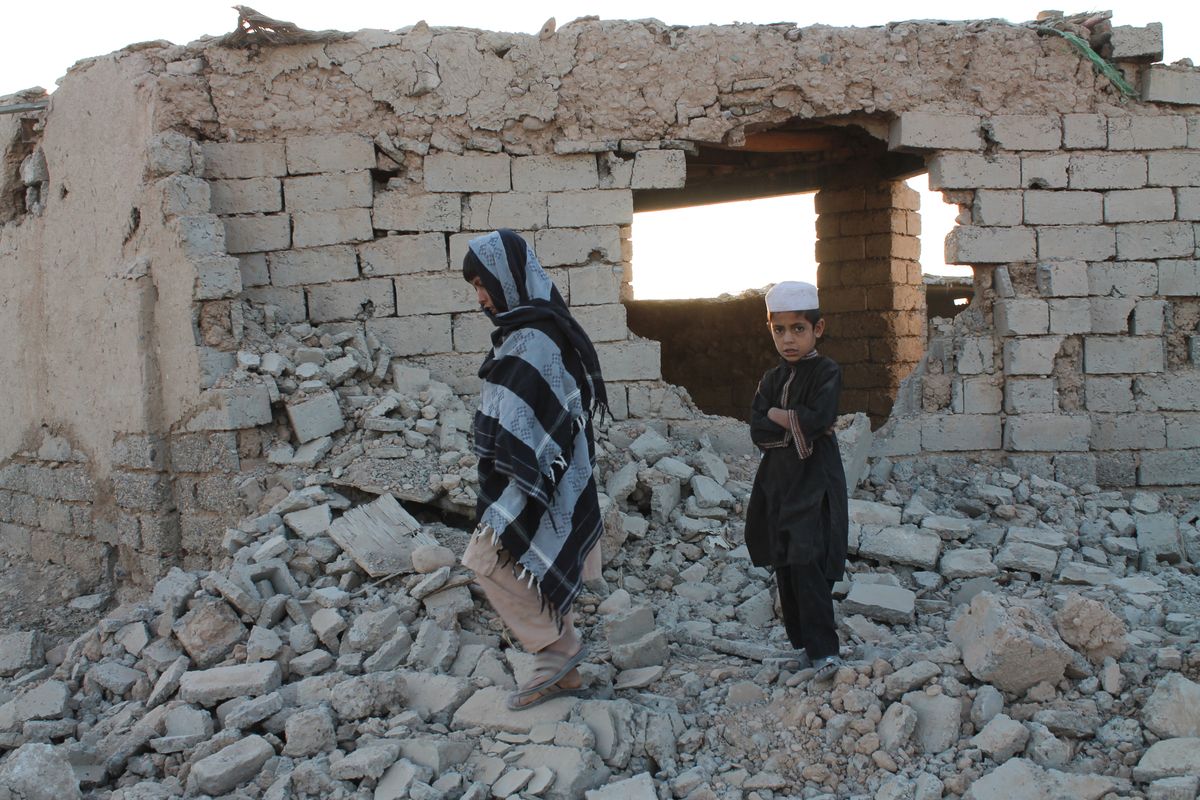 Afghan boys walk near a damaged house Saturday after airstrikes hit two weeks ago in a fight between government forces and the Taliban in Lashkar Gah, Afghanistan.  (Abdul khaliq)