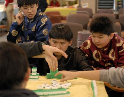 
Mike Ma, 13, Kevin Ma, 15, and David Li, 12, watch as players draw and discard mah-jongg tiles in a game during the Chinese New Year celebration at Spokane Community College on Sunday. 
 (J. Bart Rayniak / The Spokesman-Review)