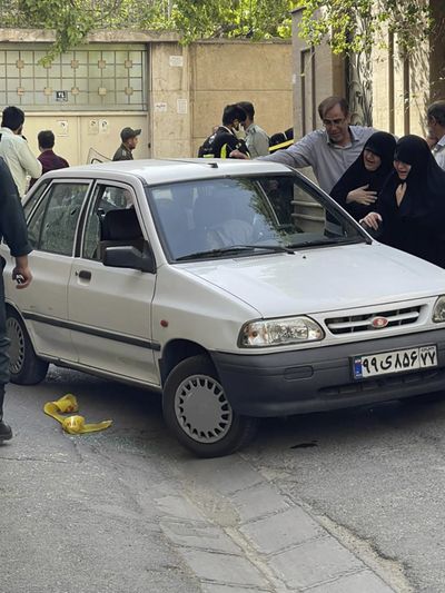 In this photo provided by Islamic Republic News Agency, IRNA, family members of Col. Hassan Sayyad Khodaei weep over his body at his car after being shot by two assailants in Tehran, Iran, Sunday, May 22, 2022. Hassan Sayyad Khodaei, a senior member of Iran's powerful Revolutionary Guard, was killed outside his home in Tehran on Sunday by unidentified gunmen on a motorbike, state TV reported.  (HOGP)