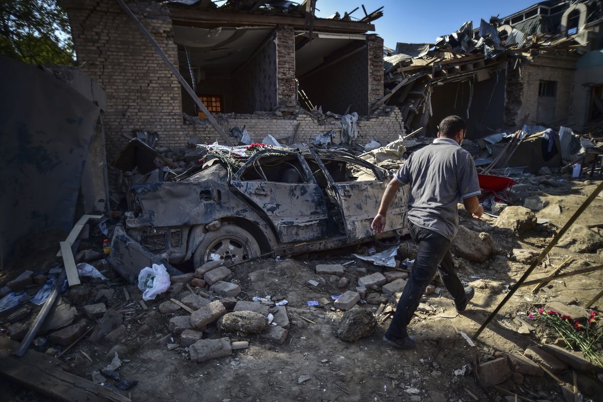 A man walks amongst the debris of damaged houses two days after shelling by Armenian