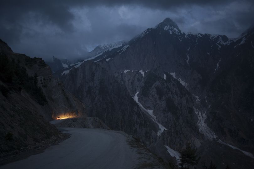 In this Monday, June 30, 2014 photo, a car moves on a serpentine road past snow-capped peaks near Zoji La in Indian-Kashmir, India. Many Tibetans say that being in the mountains make them miss their homeland. (Tsering Topgyal / Associated Press)