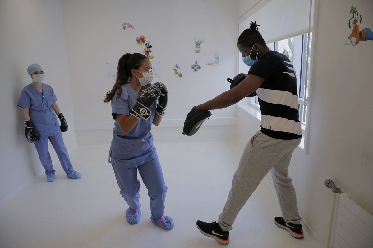 Medical worker Kenza, center and Nassima, left, attend a training session with boxer Hassan N’Dam at the Villeneuve-Saint-Georges hospital, outside Paris, on May 27, 2020. The world champion French boxer is taking his skills to hospitals, coaching staff to thank the medical profession for saving his father-in-law from the coronavirus, and giving them new confidence and relief from their stressful jobs.  (Christophe Ena)
