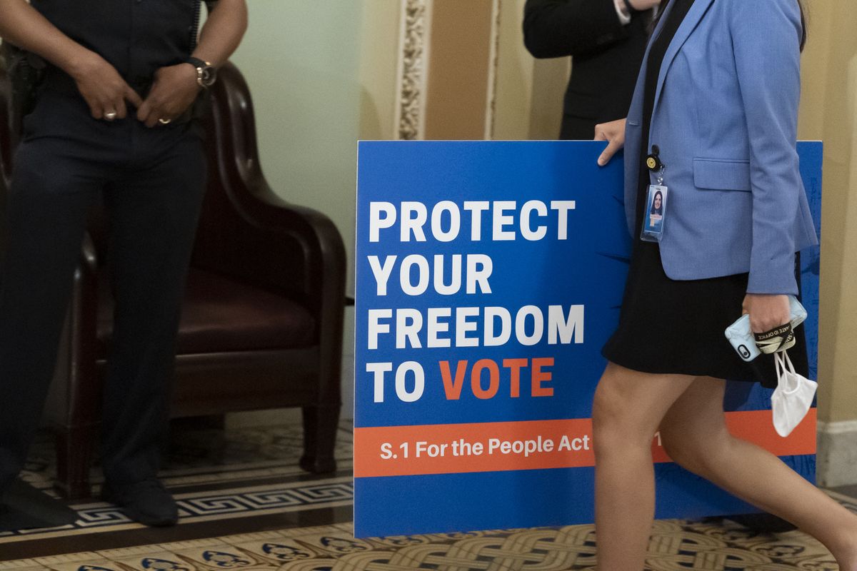 FILE - In this June 22, 2021, file photo, an aide carries a sign to the Senate floor before test vote on the For the People Act, a sweeping bill that would overhaul the election system and voting rights, at the Capitol in Washington. Both parties are bracing for a major legal fight over redistricting. Democrats need court wins more than Republicans because they control the redrawing of political maps in far fewer states than the GOP.  (Alex Brandon)
