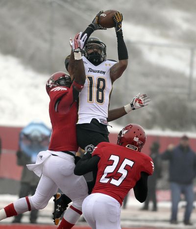 Towson Tigers wide receiver Andre Dessenberg (18) makes a reception over defenders, Eastern Washington defensive back T.J. Lee III (31) left and Eastern Washington defensive back McKenzie Murphy (25) during the first half of a FCS semifinal at Roos Field on Saturday. (Colin Mulvany)