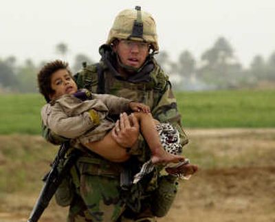 In this March 25, 2003, photo, Pfc. Joseph Dwyer, 26, from Mt. Sinai, N.Y., runs while carrying a young Iraqi boy who was injured during a heavy battle. Associated Press
 (File Associated Press / The Spokesman-Review)