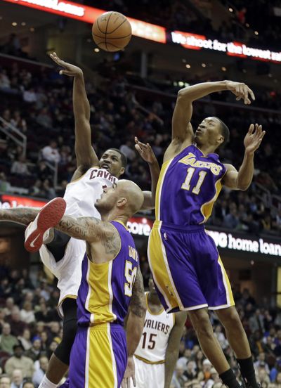 Lakers’ Robert Sacre, center, defends Cavs’ Tristan Thomspson. (Associated Press)