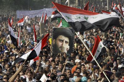 Thousands of followers of Shiite cleric Muqtada al-Sadr, pictured in the poster, converge on Firdous Square in central Baghdad on Friday for a mass prayer to protest a proposed U.S.-Iraqi security pact.  (Associated Press / The Spokesman-Review)