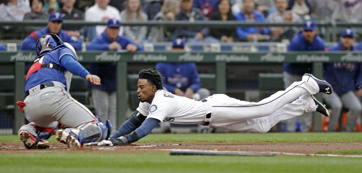Seattle’s Dee Gordon slides safely into home as Texas Rangers catcher Robinson Chirinos is late with a tag during the first inning Thursday in Seattle. (Elaine Thompson / AP)
