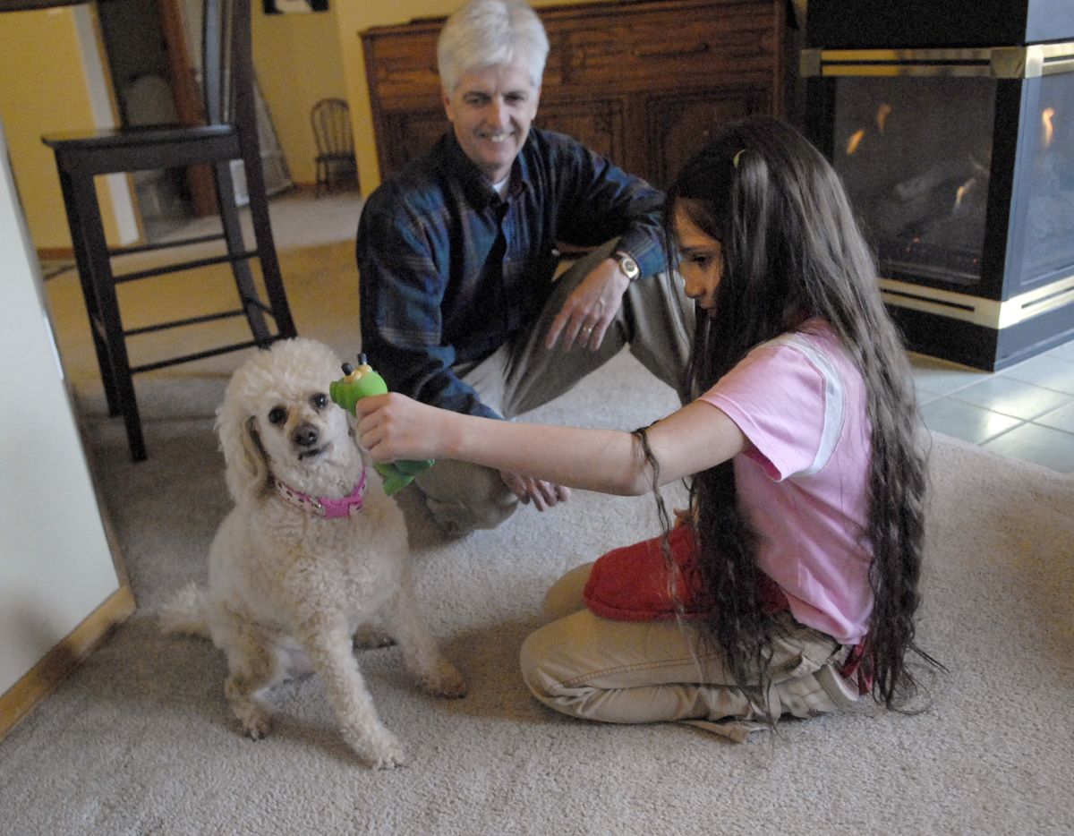 Sherry Barrett’s husband, Tim Henkel, joins Eloisa Garcia as she plays with the family poodle, Brandy. When she is older, Garcia says, “I will always remember Brandy and having fun. I will always remember Tim and Sherry. I will always remember everything.”   (J. BART RAYNIAK / The Spokesman-Review)