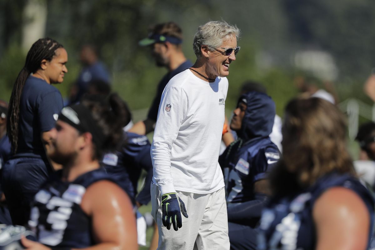 Seattle Seahawks head coach Pete Carroll smiles and he greets players at  training camp Thursday in Renton, Wash. (Ted S. Warren / AP)