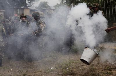 A supporter of ousted Honduras President Manuel Zelaya burns incense in a bucket near soldiers during a road blockade protest in Tegucigalpa on Thursday. The incense is believed to expel bad spirits.  (Associated Press / The Spokesman-Review)