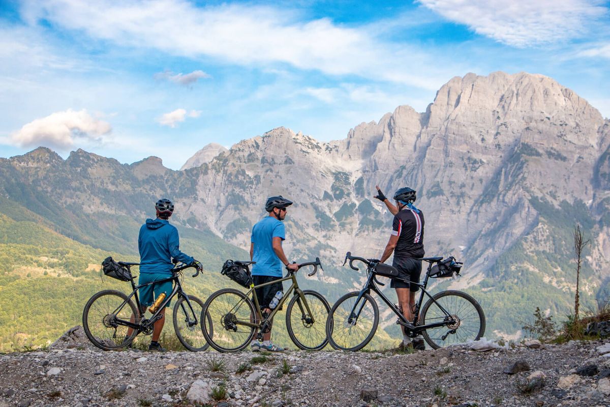 Cyclists in Theth, Albania, while traveling on the Trans Dinarica, a new cycling route that winds through eight countries in the remote Dinaric Alps. The Trans Dinarica cycling route opened officially in July 2024.  (Courtesy of TRANS DINARICA)