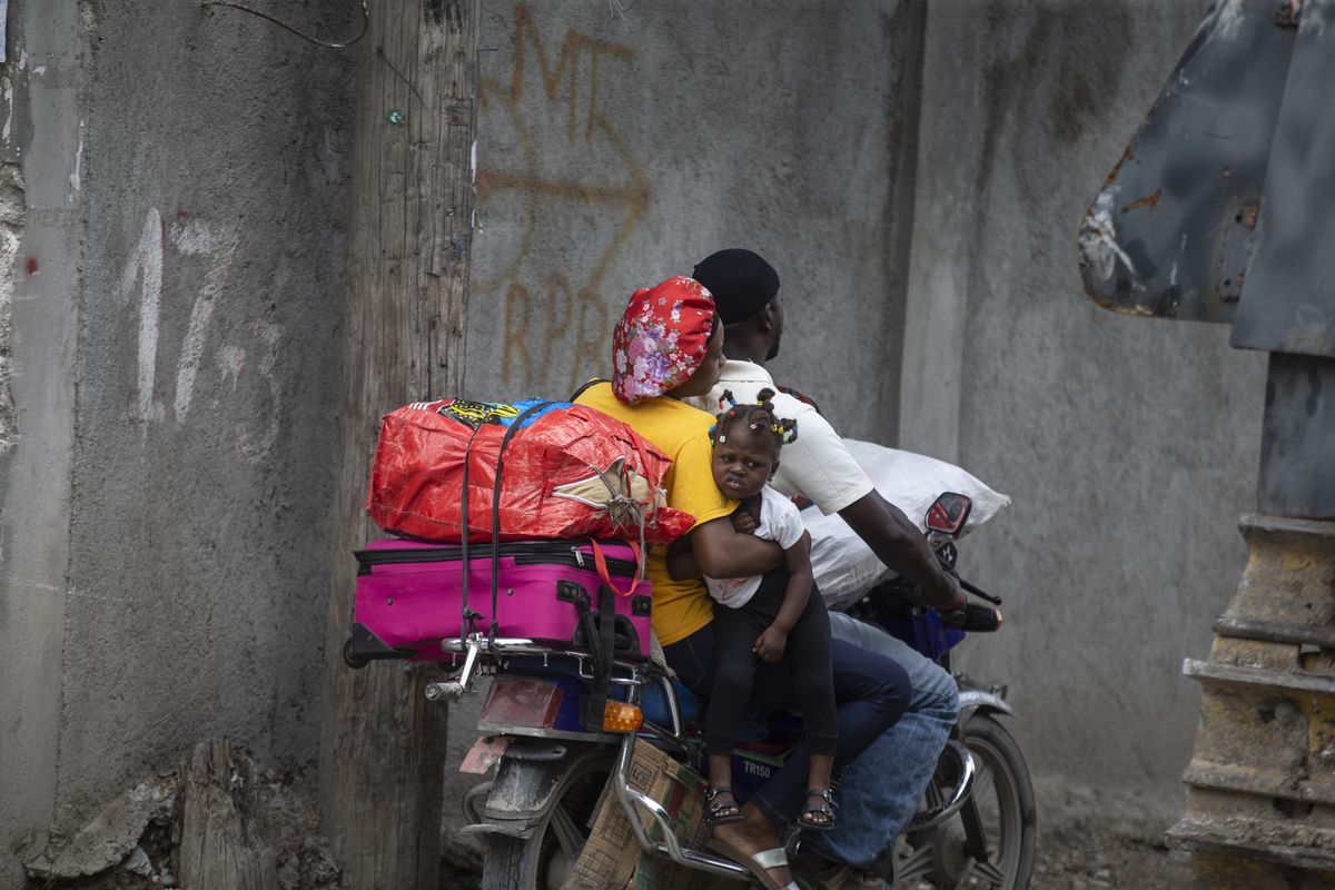 Residents travel on a motorbike as they flee their home to avoid clashes between armed gangs, in the Croix-des-Mission neighborhood of Port-au-Prince, Haiti, Thursday, April 28, 2022. Experts say the scale and duration of gang clashes, the power they are wielding and the amount of territory they control has reached levels not seen before.   (Odelyn Joseph)