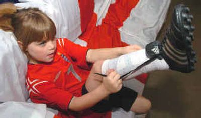 Emma Agger, 7, ties the laces of her Adidas soccer cleats at her home in Warren, Ore. Last summer her father, a longtime soccer fan originally from Leicester, took his family home to watch English 