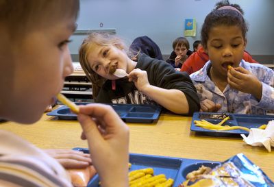 From left to right, second-graders Kurtis Kiberling, Sadie Powell and Cheyenne Coleman eat lunch in the cafeteria Friday at Holmes Elementary School in Spokane.  (Colin Mulvany / The Spokesman-Review)