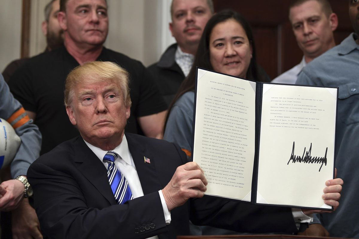 President Donald Trump holds up a proclamation on aluminum during an event in the Roosevelt Room of the White House in Washington, on Thursday. (Susan Walsh / Associated Press)