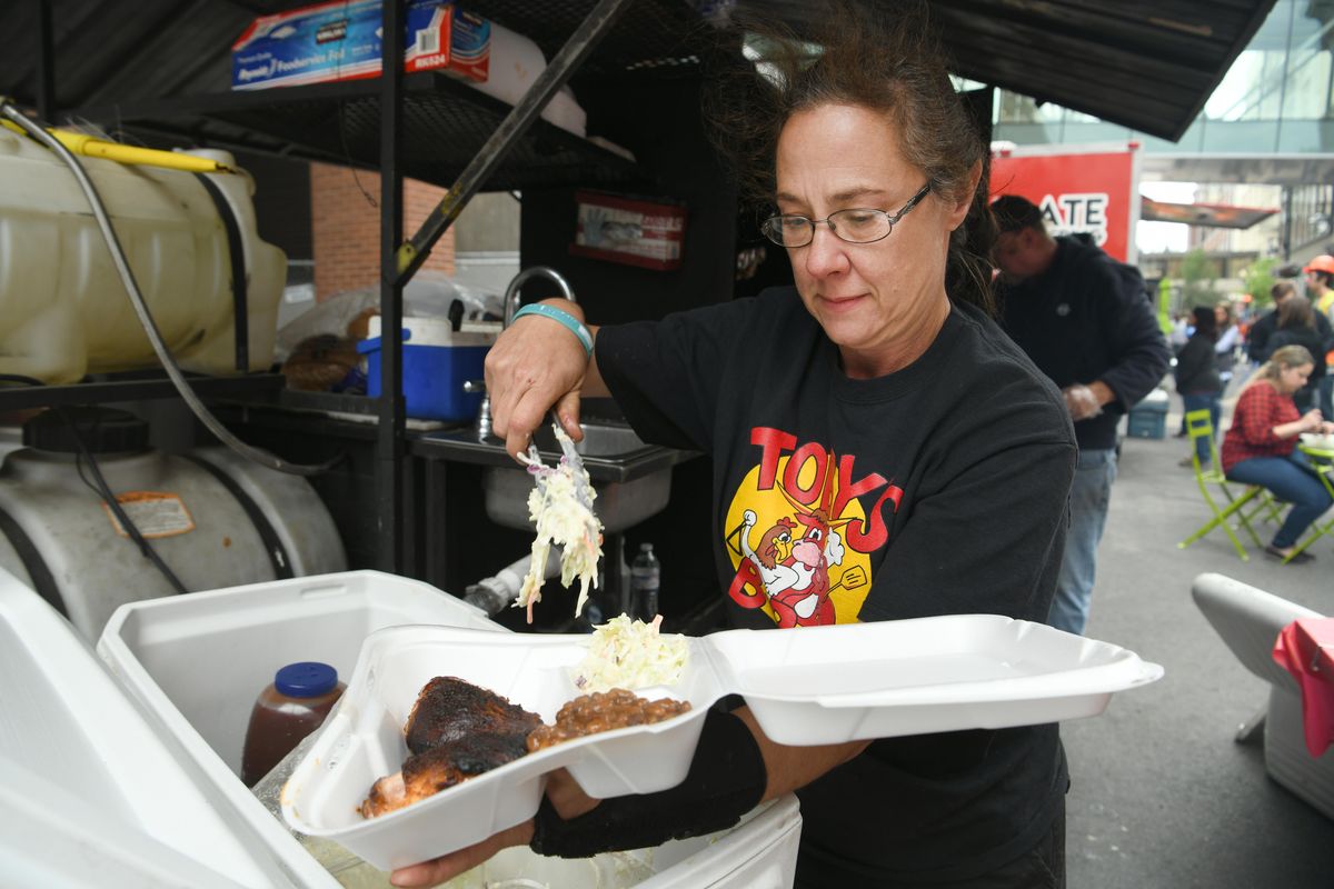 Sandra McNeilly serves up side dishes at Toby’s B-B-Q, a mobile barbecue pit set up on Wall St. in downtown Spokane Friday, June 1, 2018 during a food truck rally that will happen every Friday through the summer. (Jesse Tinsley / The Spokesman-Review)