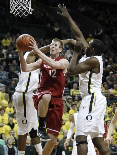 WSU’s Brock Motum drives to the basket as Oregon’s Tyrone Nared, left, and Olu Ashaolu close in. (Associated Press)