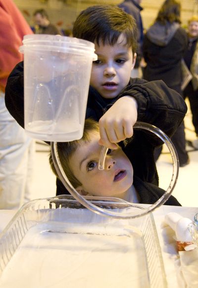 At the family science night at Jefferson Elementary School, Derek Chaves, 5, top, and his brother Kevin, 4, learn about how water moves. Whitworth University students hosted the program on April 29, which focused on sustainability and environmental and human systems. (Colin Mulvany / The Spokesman-Review)