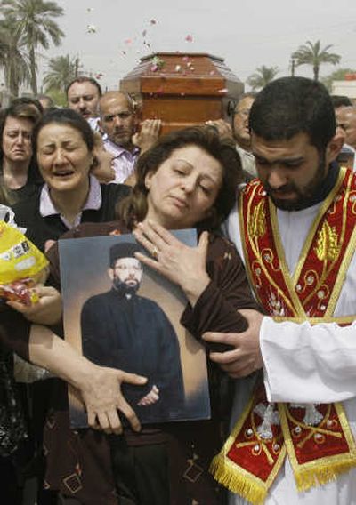 
Lamia Sheet  holds a picture of her husband, Father Youssed Adel,  as mourners carry the casket for his funeral Sunday in Baghdad. The Assyrian Orthodox priest was shot Saturday. Associated Press
 (Associated Press / The Spokesman-Review)