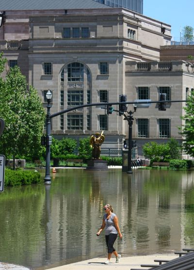 A woman walks along a flooded street past Schermerhorn Symphony Center in downtown Nashville on Monday.  (Associated Press)