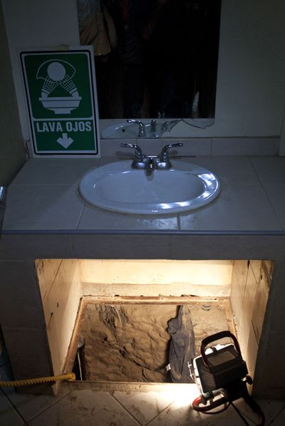 The entrance to a partial tunnel is lit by a lamp after it was found underneath a bathroom sink in a warehouse in Tijuana by the Mexican army Wednesday. (Associated Press)