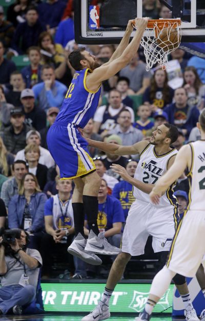 Golden State’s Andrew Bogut, left, dunks the ball against Utah’s Rudy Gobert. (Rick Bowmer / Associated Press)