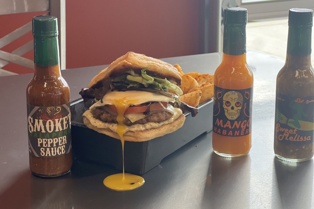 The 3 Ninjas breakfast sandwich includes choice of meat (Canadian bacon, maple-sage sausage, kielbasa or bacon), loaded onto onto a square croissant and topped with caramelized onions, Swiss cheese, egg and balsamic glaze. Here, it is surrounded by 3 Ninjas specialty hot sauces. (Courtesy)
