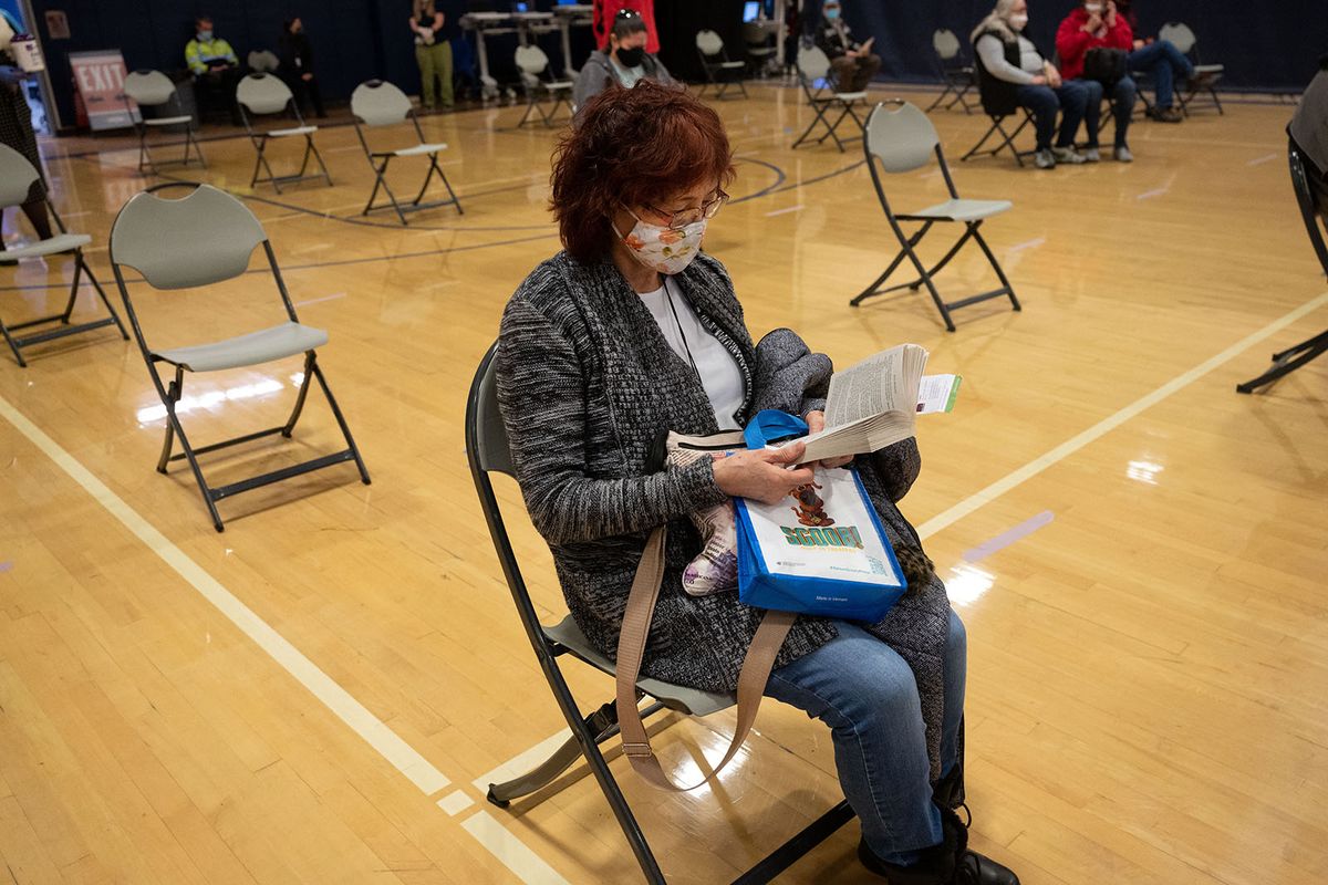 After receiving her first dose of the Moderna COVID-19 vaccine, Eiko Matsunaga reads a book in the recovery area Friday in Gonzaga’s Martin Centre. (COLIN MULVANY/THE SPOKESMAN-REVIEW)