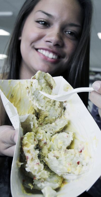 Maria Turner poses earlier this month with her dish of baked potatoes mixed with sour cream, bacon bits, melted cheese and croutons during lunch at Gardiner High School in Gardiner, Maine. (Associated Press)