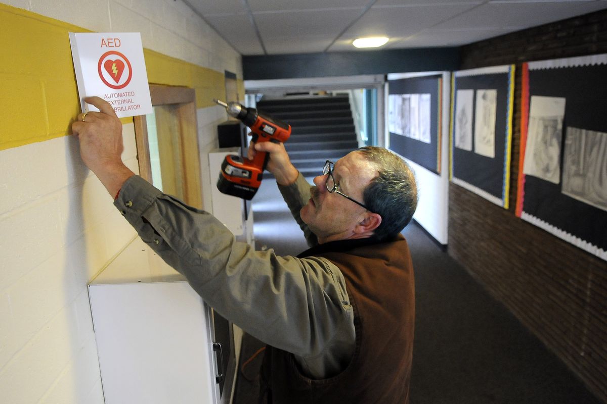 Randy Wright, facilities director at Northwest Christian Schools, drills holes for a sign and wall-mounted enclosure for an automated external defibrillator at the high school in Colbert. Wright’s son Josh  died suddenly  while on a cross country training run in August.  (Dan Pelle)