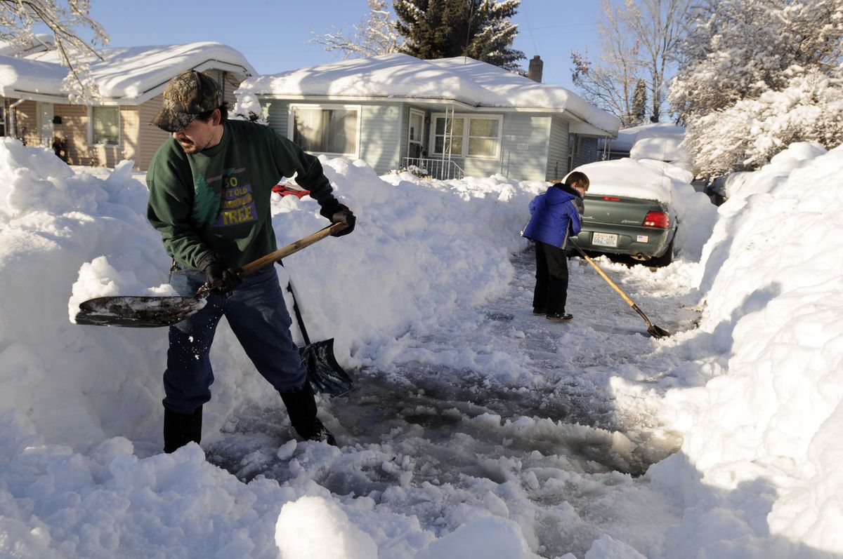 Kevin Newman, left, a Cubmaster for a pack of Cub Scouts, digs out a North Side driveway with his 7-year-old son, Kaden, right, as a service project with the local Boy Scout community Friday. Scout officials set up a call-in line for help with the snow and the Scouts have more work than they can handle.  (Jesse Tinsley / The Spokesman-Review)