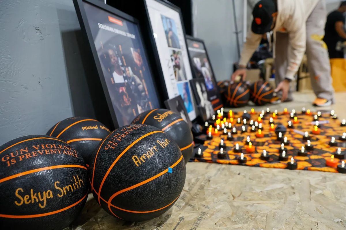 Jeremy Winzer arranges basketballs, each with the name of a gun violence victim, around a memorial at Hoop to Heal on Tuesday night.  (Jennifer Buchanan/Seattle Times)