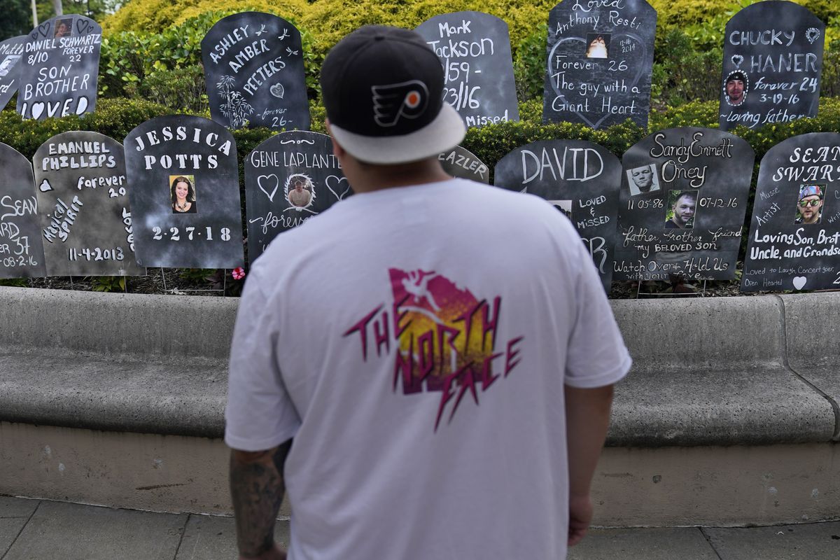 A man looks at cardboard gravestones with the names of victims of opioid abuse outside the courthouse where the Purdue Pharma bankruptcy is taking place in White Plains, N.Y., Monday, Aug. 9, 2021. Purdue Pharma's quest to settle thousands of lawsuits over the toll of OxyContin is entering its final phase with the grudging acceptance of most of those with claims against the company. A confirmation hearing is to open in U.S. Bankruptcy Court on Thursday for a deal that removes control of the company from members of the wealthy Sackler family and requires them to contribute $4.5 billion to opioid abatement While most states and others with claims have signed on, there's still deep anger that Sackler family members would receive protection from lawsuits under the deal.  (Seth Wenig)