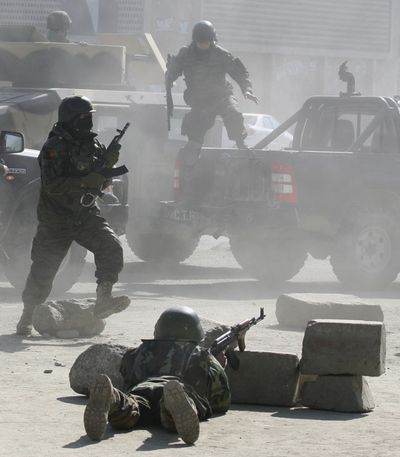 Afghan security forces run for the Afghan Justice Ministry following an attack in Kabul, Afghanistan on Wednesday.  The Taliban claimed responsibility for the attacks, which killed 20 and injured many.  (Associated Press / The Spokesman-Review)