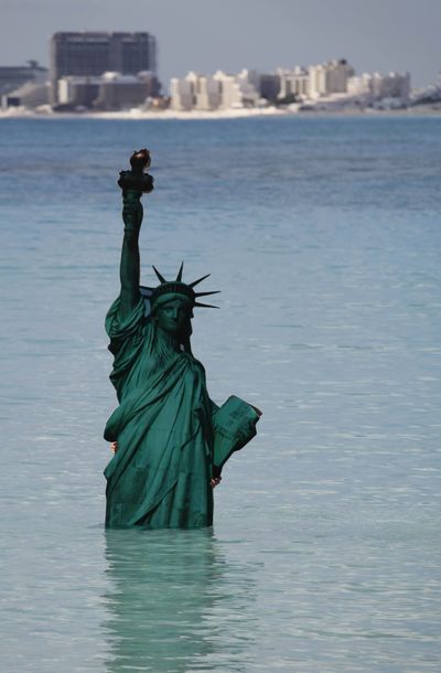 An activist from Greenpeace holds an image of the Statue of Liberty in the water during the United Nations Climate Change Conference in Cancun, Mexico, on Wednesday.  (Associated Press)